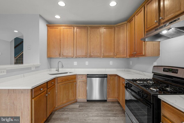 17504 Cajun Ct, Dumfries, VA 22025 - kitchen featuring gas range oven, dishwasher, a sink, under cabinet range hood, and light wood-style flooring