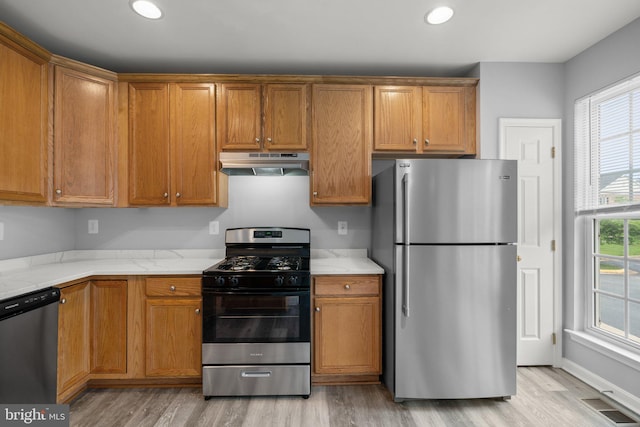 17504 Cajun Ct, Dumfries, VA 22025 - kitchen featuring appliances with stainless steel finishes, under cabinet range hood, light wood-style flooring, brown cabinetry, and recessed lighting