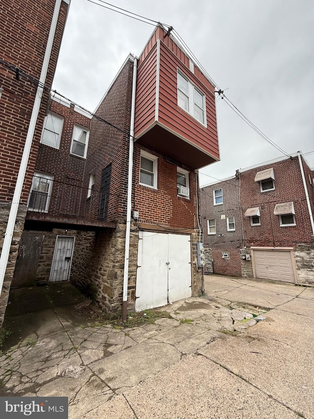 6412 N Sydenham St, Philadelphia, PA 19126 - rear view of house featuring a garage, brick siding, and driveway