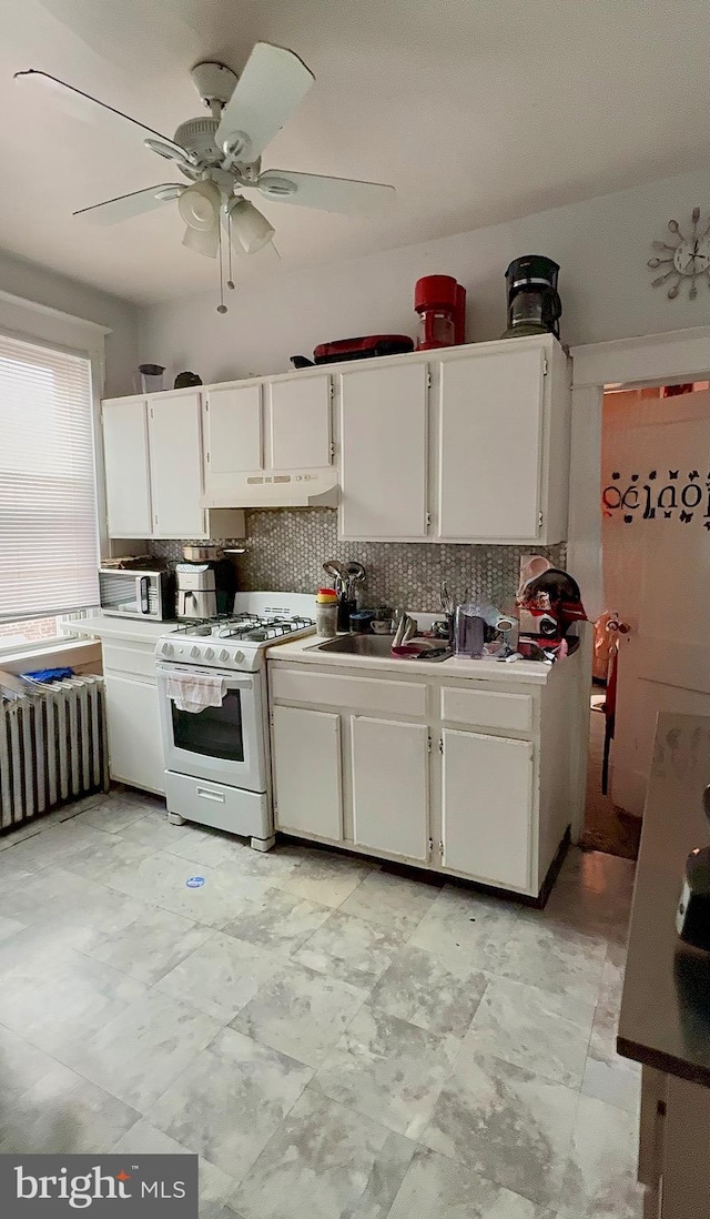 6412 N Sydenham St, Philadelphia, PA 19126 - kitchen featuring white gas range, under cabinet range hood, white cabinets, tasteful backsplash, and ceiling fan