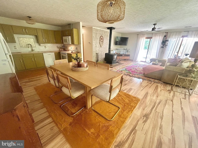 415 Rolly Rd, Mount Jackson, VA 22842 - dining area with light wood-style floors, a wood stove, a textured ceiling, and a ceiling fan