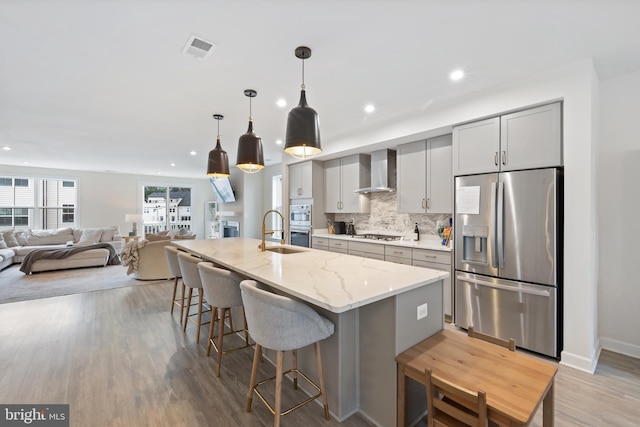 12363 Azure Ln Unit 42, Fairfax, VA 22033 - kitchen with stainless steel appliances, wall chimney exhaust hood, a sink, backsplash, and a kitchen bar