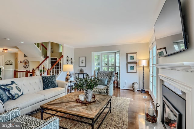 11920 Mays Chapel Rd, Lutherville Timonium, MD 21093 - living room featuring a fireplace with flush hearth, stairs, baseboards, wood finished floors, and crown molding