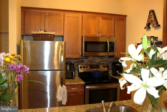 600 Moonglow Rd Unit 302, Odenton, MD 21113 - kitchen featuring appliances with stainless steel finishes, backsplash, light stone countertops, and brown cabinets