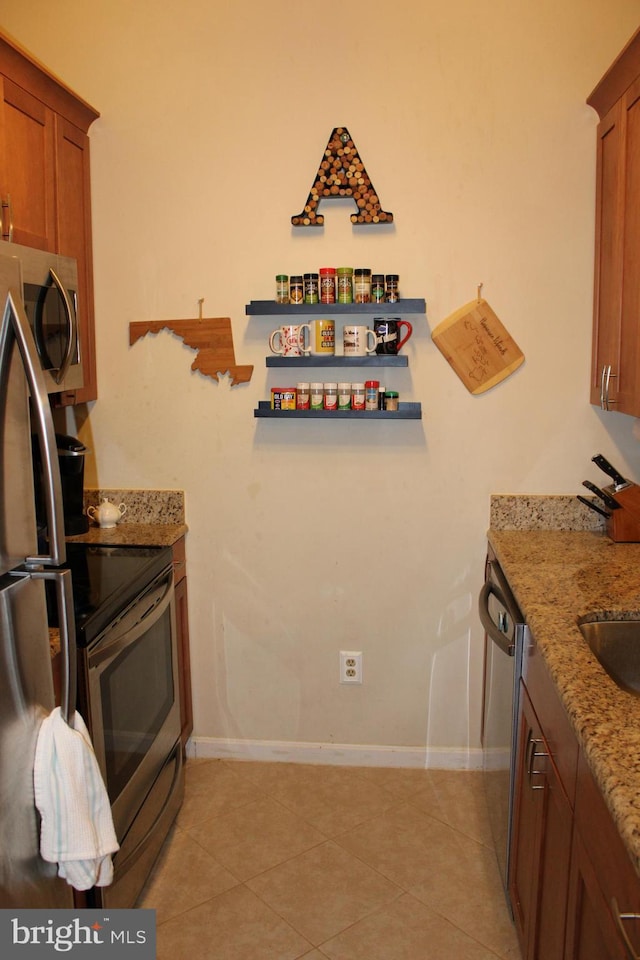 600 Moonglow Rd Unit 302, Odenton, MD 21113 - kitchen with appliances with stainless steel finishes, brown cabinets, baseboards, light stone countertops, and light tile patterned flooring