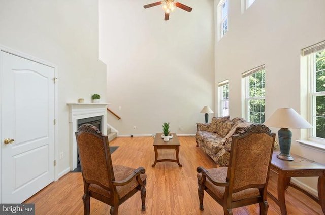 8 Rivers Edge Ter, Indian Head, MD 20640 - living room featuring a towering ceiling, light wood-style flooring, a glass covered fireplace, ceiling fan, and baseboards