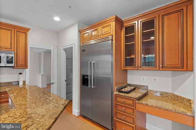 14603 Turner Wootton Pkwy, Upper Marlboro, MD 20774 - kitchen featuring appliances with stainless steel finishes, brown cabinets, light stone counters, glass insert cabinets, and light wood-style flooring