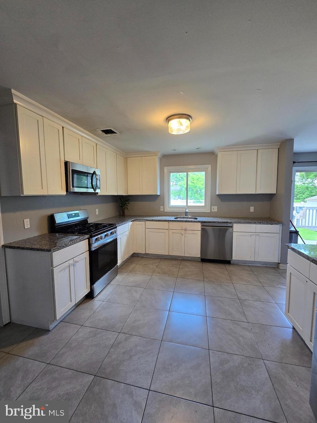 355 Leonard Ave, Hamilton, NJ 08619 - kitchen featuring appliances with stainless steel finishes, healthy amount of natural light, light tile patterned flooring, and dark stone countertops