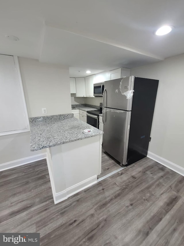 113 15th St SE, Washington, DC 20003 - kitchen featuring stainless steel appliances, a peninsula, white cabinets, wood finished floors, and light stone counters