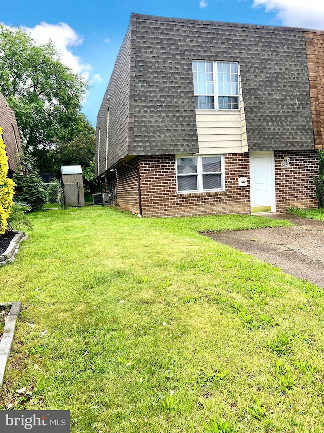 9939 Wingtip Rd, Philadelphia, PA 19115 - view of side of home with brick siding, roof with shingles, mansard roof, and a yard