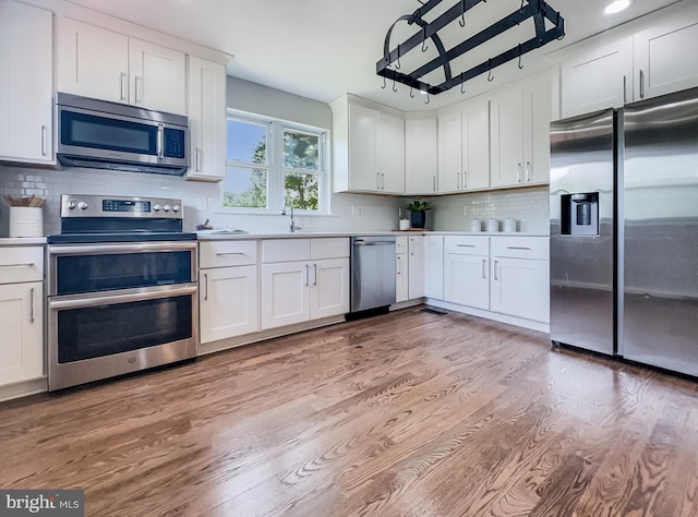 4920 Ed Mcclain Rd, Monrovia, MD 21770 - kitchen featuring stainless steel appliances, backsplash, light wood-type flooring, white cabinetry, and light countertops