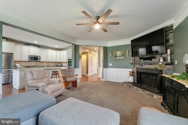 43268 Heavenly Cir, Leesburg, VA 20176 - living area with ornamental molding, ceiling fan, a fireplace, wainscoting, and a decorative wall