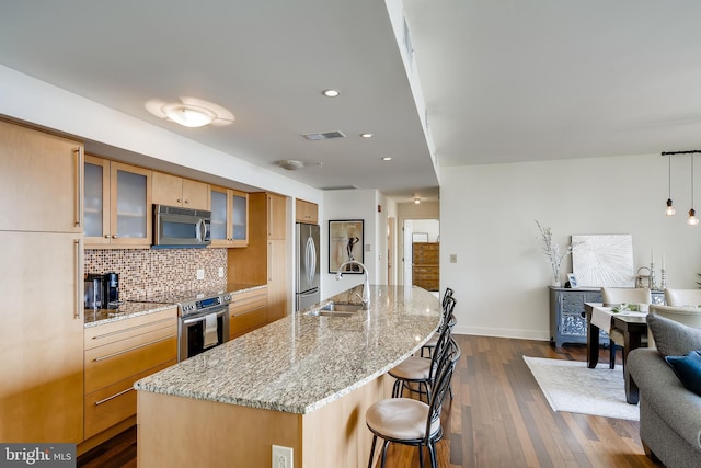 675 President St Unit 2105, Baltimore, MD 21202 - kitchen featuring stainless steel appliances, a sink, dark wood-type flooring, a kitchen breakfast bar, and decorative backsplash