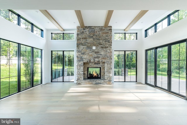 918 Ethan Allen Rd, Berwyn, PA 19312 - unfurnished living room with a high ceiling, beam ceiling, a stone fireplace, and wood finished floors