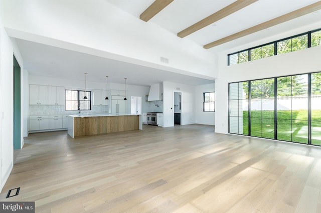 918 Ethan Allen Rd, Berwyn, PA 19312 - unfurnished living room with a towering ceiling, beam ceiling, light wood-type flooring, and a sink