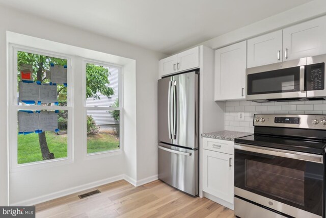 13929 Carthage Cir, Burtonsville, MD 20866 - kitchen with stainless steel appliances, light wood-style flooring, white cabinets, light stone counters, and baseboards