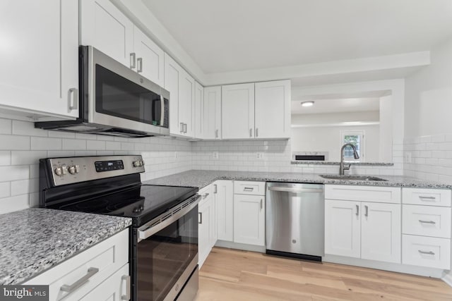 13929 Carthage Cir, Burtonsville, MD 20866 - kitchen featuring appliances with stainless steel finishes, a sink, white cabinetry, light wood-style floors, and decorative backsplash