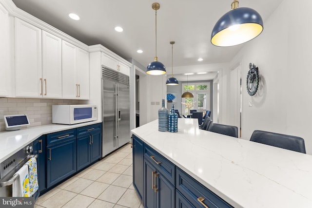 22962 Lois Ln, Brambleton, VA 20148 - kitchen with white microwave, built in refrigerator, blue cabinets, wall oven, and recessed lighting