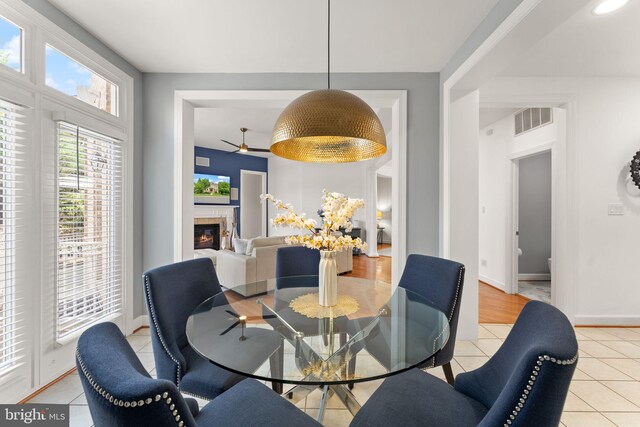 22962 Lois Ln, Brambleton, VA 20148 - dining area with light tile patterned floors, ceiling fan, a glass covered fireplace, and baseboards
