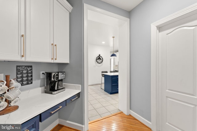 22962 Lois Ln, Brambleton, VA 20148 - kitchen with blue cabinets, white cabinetry, baseboards, and light wood finished floors