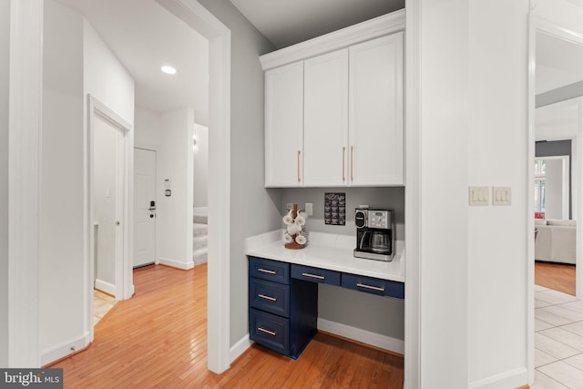 22962 Lois Ln, Brambleton, VA 20148 - kitchen featuring blue cabinets, white cabinetry, light wood finished floors, light countertops, and baseboards