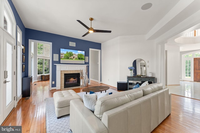 22962 Lois Ln, Brambleton, VA 20148 - living room featuring a tiled fireplace, ceiling fan, light wood finished floors, and baseboards