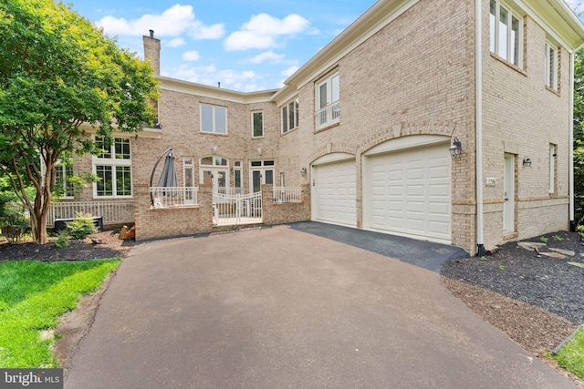 22962 Lois Ln, Brambleton, VA 20148 - view of front of home with driveway, an attached garage, a chimney, and brick siding