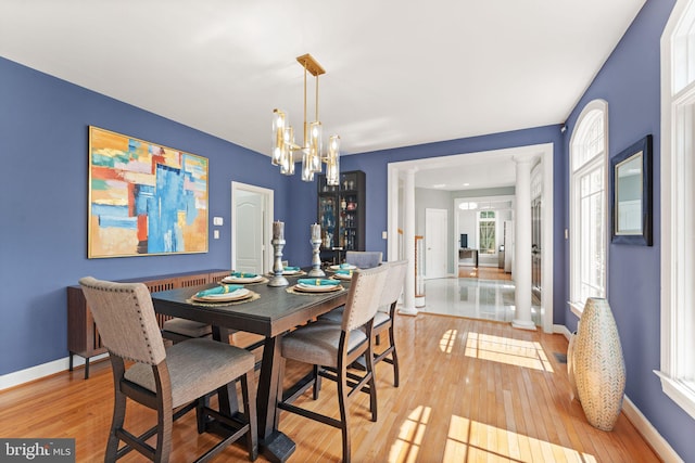 22962 Lois Ln, Brambleton, VA 20148 - dining room featuring light wood finished floors, baseboards, decorative columns, and a chandelier