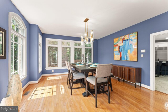 22962 Lois Ln, Brambleton, VA 20148 - dining space featuring a chandelier, healthy amount of natural light, light wood finished floors, and baseboards