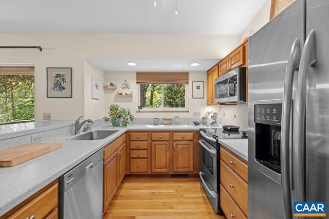 213 Turkey Ridge Rd, Charlottesville, VA 22903 - kitchen with stainless steel appliances, a sink, light wood-style flooring, brown cabinetry, and light countertops