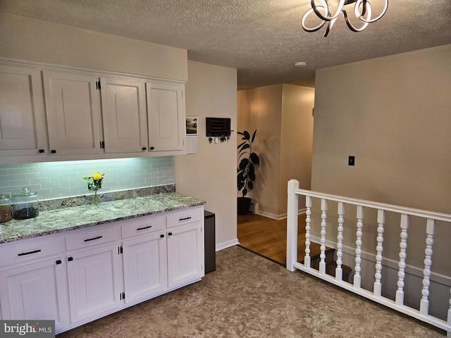 1222 Pinehurst Rd, Staunton, VA 24401 - kitchen featuring a chandelier, white cabinetry, decorative backsplash, light stone countertops, and a textured ceiling