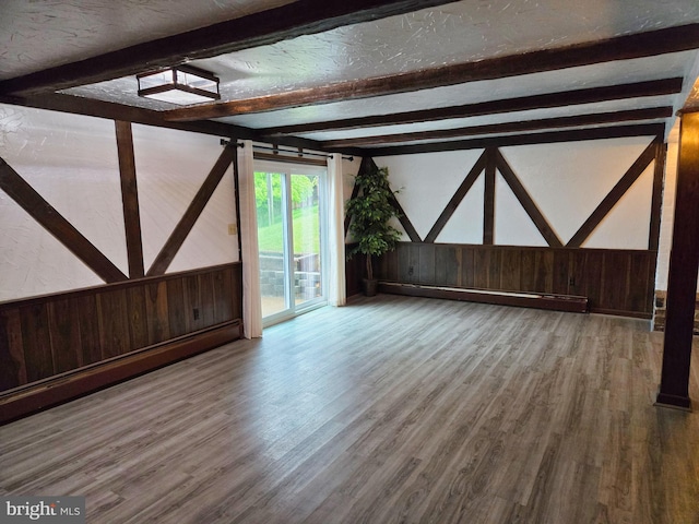 1222 Pinehurst Rd, Staunton, VA 24401 - unfurnished living room with wooden walls, beamed ceiling, wood finished floors, baseboard heating, and wainscoting