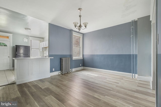 6745 Woodley, Dundalk, MD 21222 - unfurnished living room featuring radiator heating unit, a chandelier, light wood-type flooring, baseboards, and a sink