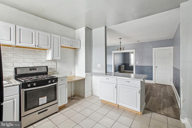 6745 Woodley, Dundalk, MD 21222 - kitchen with stainless steel gas range oven, baseboards, white cabinetry, backsplash, and a peninsula