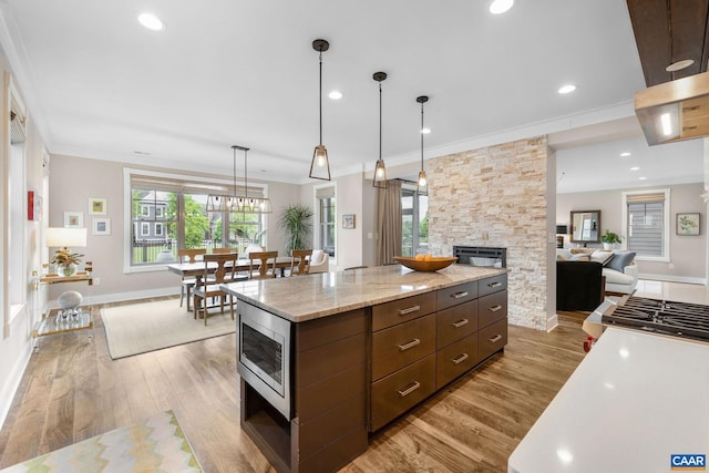729 Highgate Row, Crozet, VA 22932 - kitchen with stainless steel microwave, light wood-type flooring, a fireplace, crown molding, and hanging light fixtures