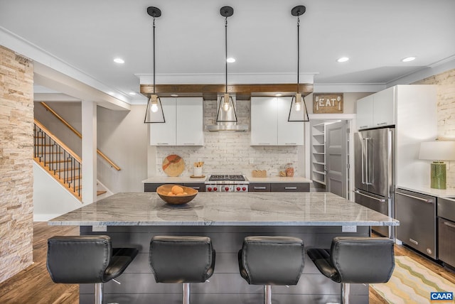 729 Highgate Row, Crozet, VA 22932 - kitchen with stainless steel appliances, a kitchen breakfast bar, wall chimney exhaust hood, light wood-type flooring, and crown molding