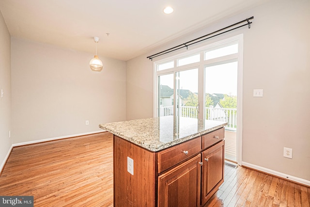 11919 Little Seneca Pkwy, Clarksburg, MD 20871 - kitchen with light wood finished floors, baseboards, brown cabinetry, light stone counters, and pendant lighting