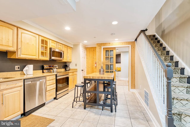 1337 Harvard St NW Unit 1, Washington, DC 20009 - kitchen featuring stainless steel appliances, light brown cabinetry, crown molding, glass insert cabinets, and light tile patterned floors