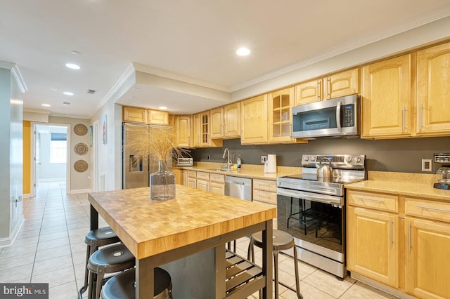 1337 Harvard St NW Unit 1, Washington, DC 20009 - kitchen featuring appliances with stainless steel finishes, light tile patterned flooring, light brown cabinetry, a sink, and crown molding