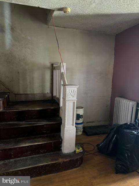 518 S 55th St, Philadelphia, PA 19143 - staircase featuring radiator, wood finished floors, and a textured ceiling