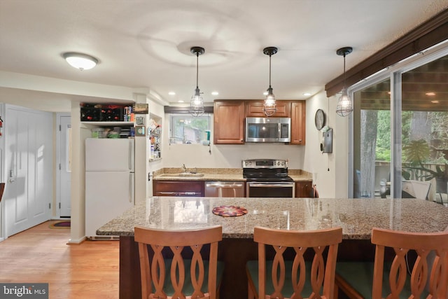 3615 22nd St N, Arlington, VA 22207 - kitchen with stainless steel appliances, a sink, brown cabinetry, light wood-style floors, and a kitchen bar