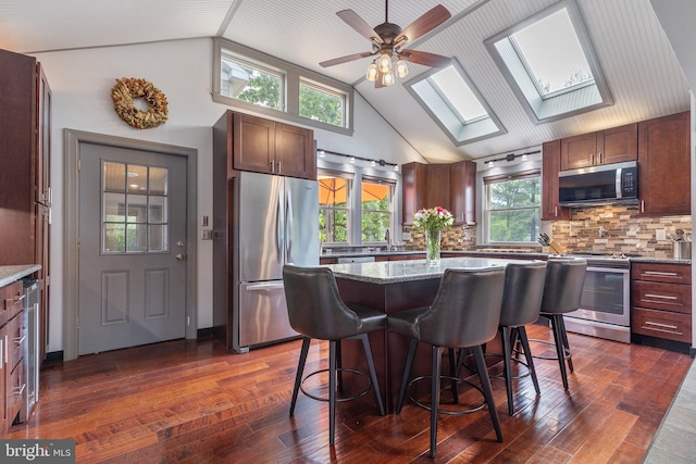 1104 N Pleasantview Rd, Pottstown, PA 19464 - kitchen with stainless steel appliances, vaulted ceiling, dark wood finished floors, a breakfast bar, and backsplash