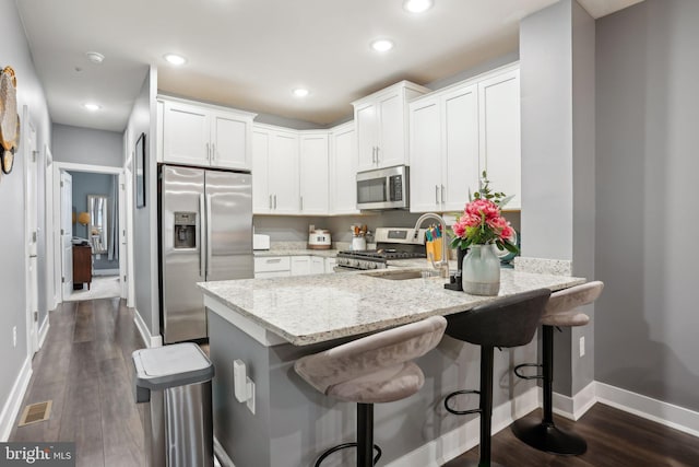 117 King St Unit A, Bensalem, PA 19020 - kitchen featuring stainless steel appliances, a peninsula, light stone counters, baseboards, and a sink