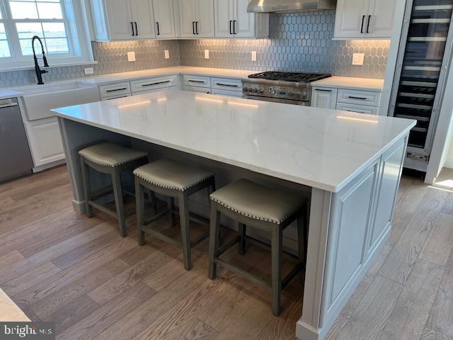 11 Selma Dr, Manahawkin, NJ 08050 - kitchen with beverage cooler, light wood-type flooring, a sink, stainless steel appliances, and range hood