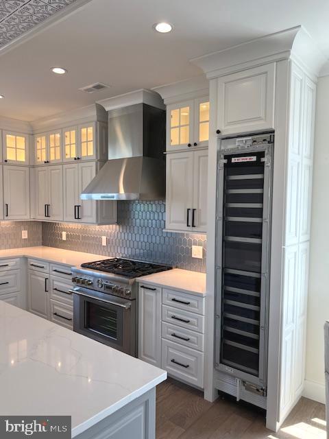 11 Selma Dr, Manahawkin, NJ 08050 - kitchen with wine cooler, wall chimney range hood, high end stove, white cabinetry, and recessed lighting