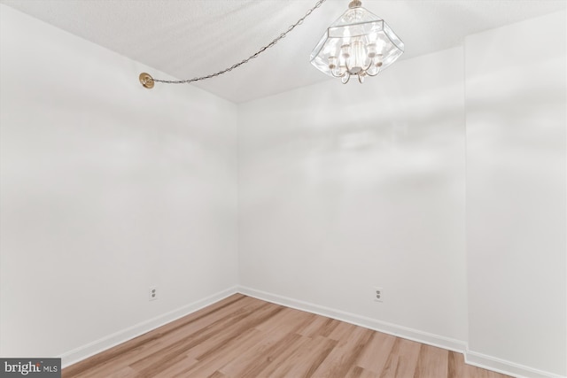 801 N Howard St Unit 305, Alexandria, VA 22304 - spare room with a chandelier, light wood-type flooring, and baseboards