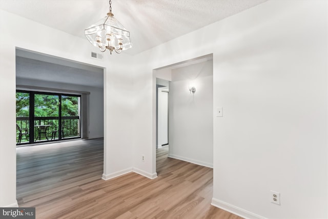 801 N Howard St Unit 305, Alexandria, VA 22304 - empty room with a chandelier, baseboards, light wood-style flooring, and a textured ceiling