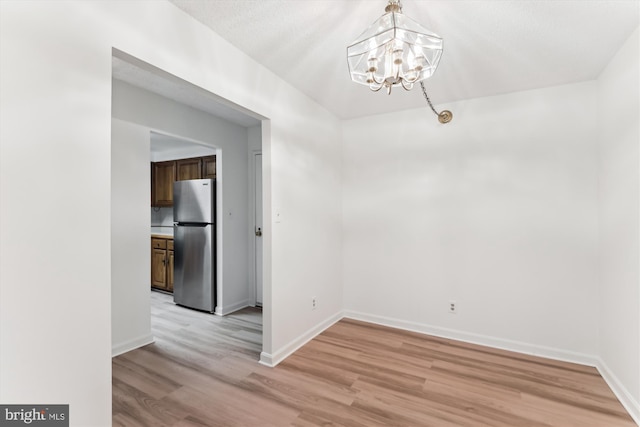 801 N Howard St Unit 305, Alexandria, VA 22304 - unfurnished dining area with a chandelier, light wood-type flooring, and baseboards