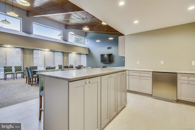 801 N Howard St Unit 305, Alexandria, VA 22304 - kitchen featuring a towering ceiling, wooden ceiling with exposed beams, open floor plan, light countertops, and a breakfast bar area