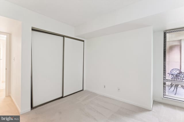 801 N Howard St Unit 305, Alexandria, VA 22304 - unfurnished bedroom with light carpet, a closet, baseboards, and multiple windows
